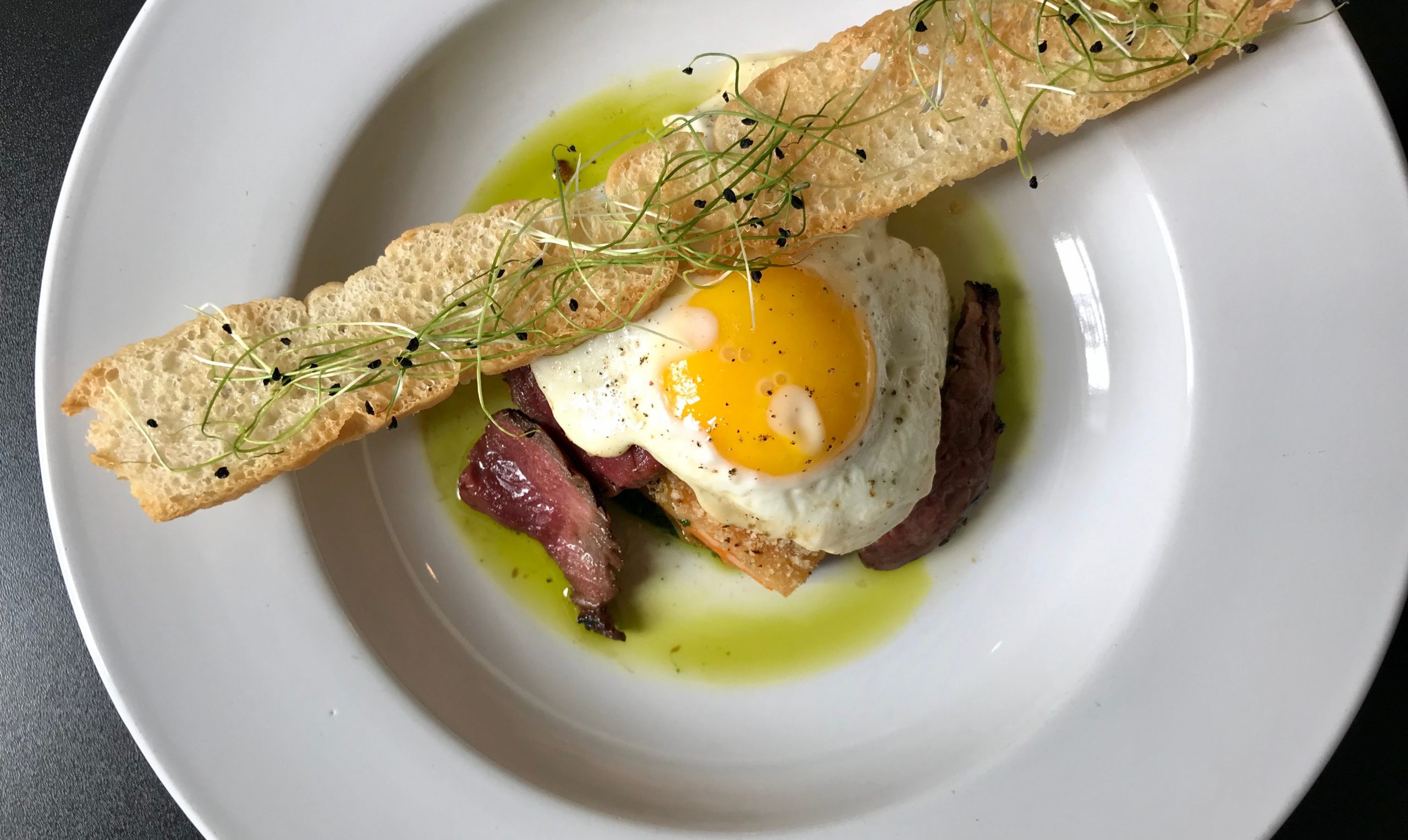 A contemprary breakfast from S2S. Egg, Brisket, and topped with some bread.